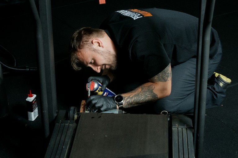 Elite Gym maintenance servicing a treadmill.